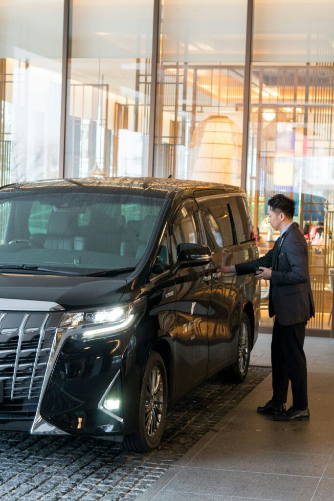 Chauffeur in a suit opening the door of a black luxury vehicle